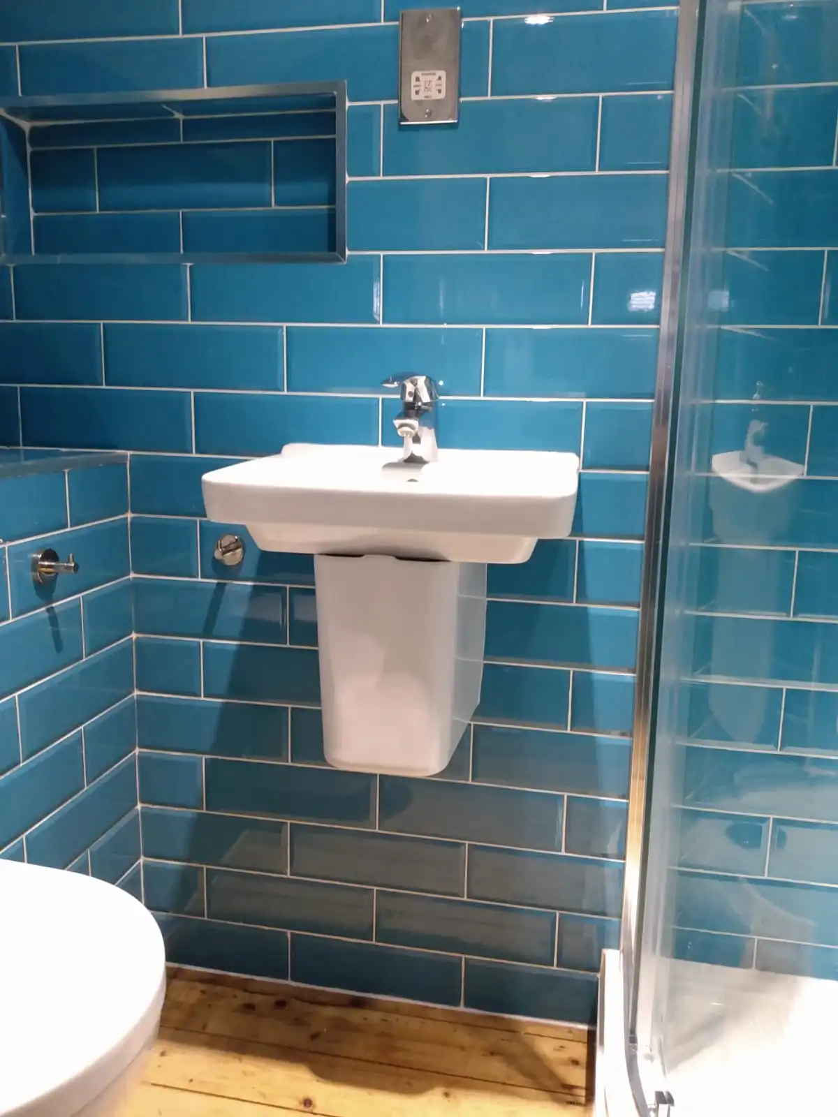 Bathroom shower installation with tiled walls, basin and fitted plumbing fixtures