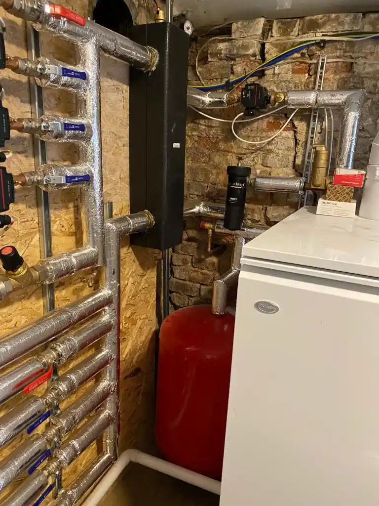 Boiler and heating system with insulated pipework, pumps and expansion vessel