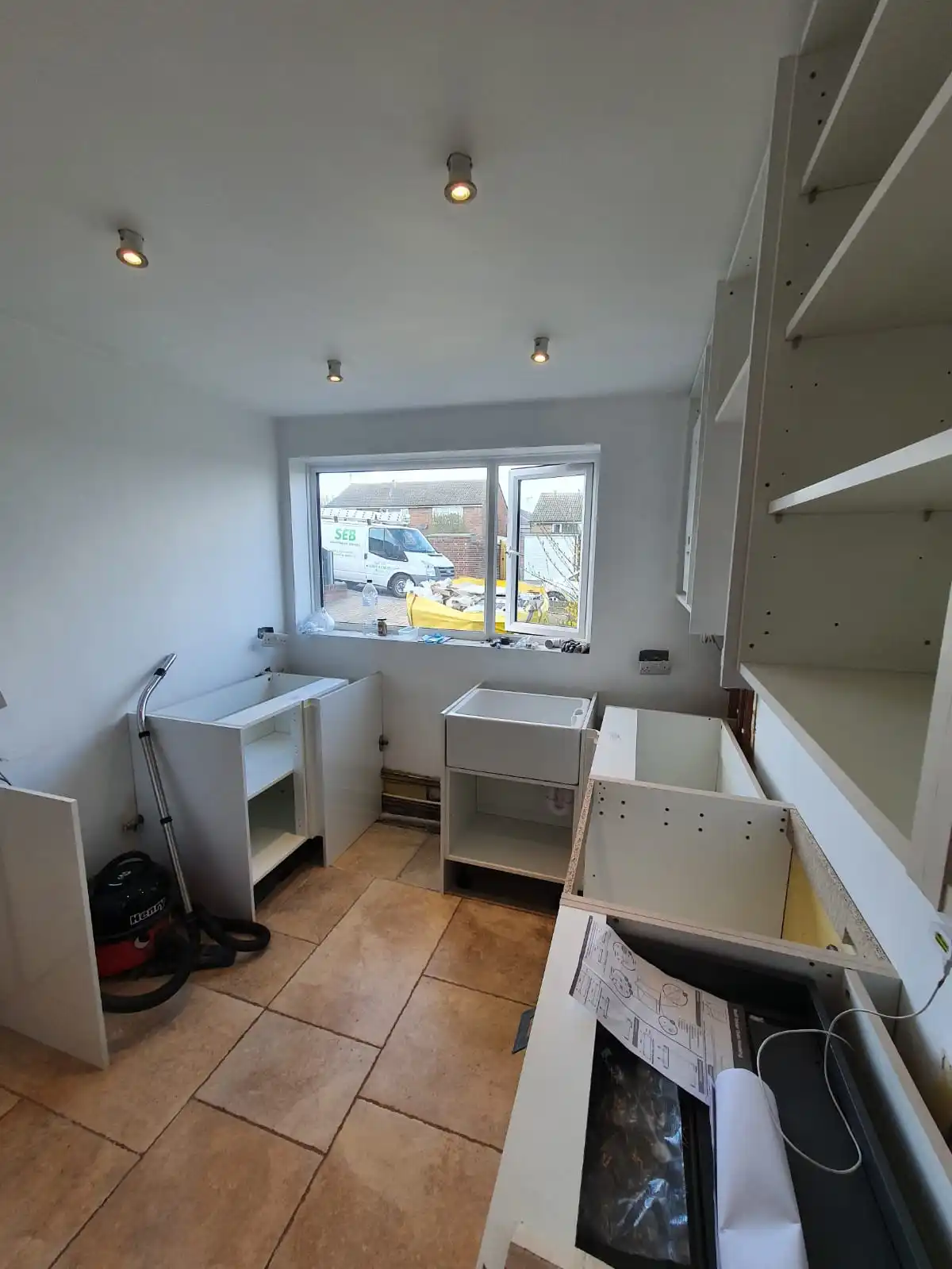Kitchen plumbing installation in progress with sink unit, cabinets and exposed pipework
