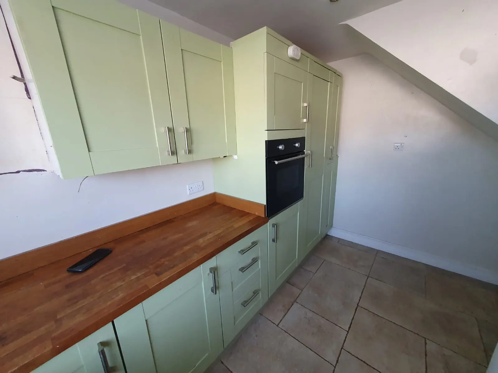 Finished kitchen installation with fitted cabinets, worktop and integrated oven